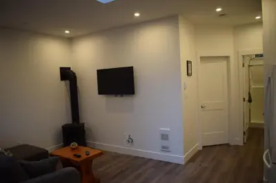a living room with a couch and a tv on the wall at The Purple Door Carriage House in Lantzville