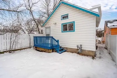 a white house with a blue roof in the snow at Triceratops Landing I Fire Place I Games I Netflix in Drumheller