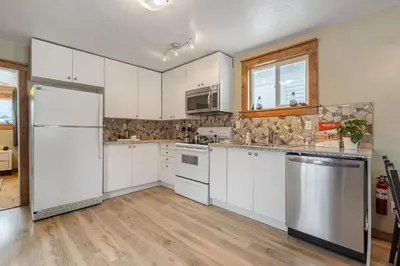 a kitchen with white cabinets and a stainless steel refrigerator at Triceratops Landing I Fire Place I Games I Netflix in Drumheller