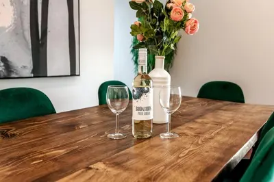 a bottle of wine and two wine glasses on a wooden table at Exotic,LUSH,Rainforest,CR,Suite,King,U/G,Wifi in Edmonton