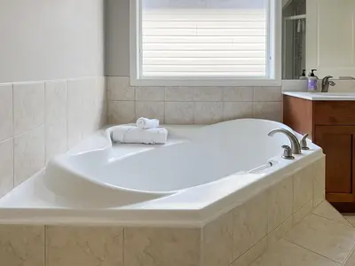 a large white tub in a bathroom with a window at Serene and Secure Home Sweet Home with Office, 15 mins to Airport, 20 mins to Downtown, 90 mins to Banff in Calgary