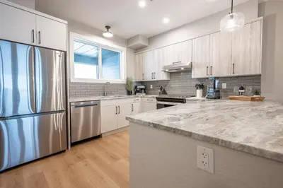 a kitchen with a stainless steel refrigerator and wooden cabinets at Grizzly Ridge Getaway - Private Hot Tub, Mtn View & Sleeps 11 in Big White
