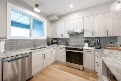 a kitchen with white cabinets and a window at Grizzly Ridge Getaway - Private Hot Tub, Mtn View & Sleeps 11 in Big White