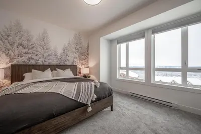 a bedroom with a large bed and windows at Grizzly Ridge Getaway - Private Hot Tub, Mtn View & Sleeps 11 in Big White