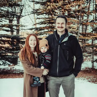 a man and a woman holding a baby in the snow at Craftsman's Loft - Heritage charm - AC - 5 min DT in Calgary
