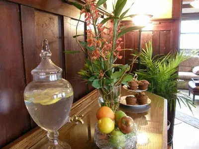 a table with a drink and a vase of water at Fisher House Victoria Bed and Breakfast in Victoria