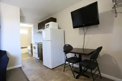 a kitchen with a small table and a white refrigerator at Blue Bell Inn in Fort Nelson