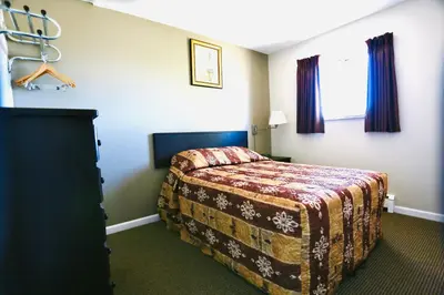 a hotel room with a bed and a window at Blue Bell Inn in Fort Nelson