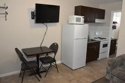a kitchen with a small table and a white refrigerator at Blue Bell Inn in Fort Nelson