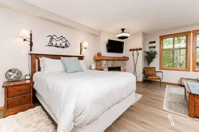 a bedroom with a large white bed and a fireplace at The Powder Nook, Hot Pools, Mile 1 Express Chair in Panorama