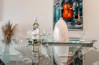 a glass table with wine glasses and a bottle on it at Steamy Romantic Greek Corneer Suite King U/G Wifi in Edmonton