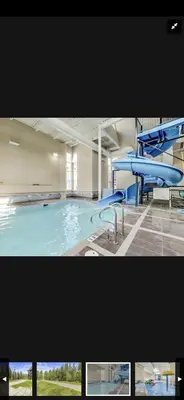 a large swimming pool with a blue slide at Canmore Mountain Retreat. Hot Tub, Pool, King Bed! in Canmore