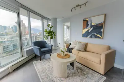a living room with a couch and a chair and a table at Downtown King Suite-Surround Views-Pool/Gym/Parkng in Vancouver