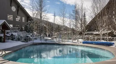 a swimming pool covered in snow next to a building at The best ski in ski out two bedroom condo at Aspens in Whistler