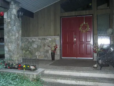 a red door of a house with a bench and flowers at Misty Meadows B and B in Langford