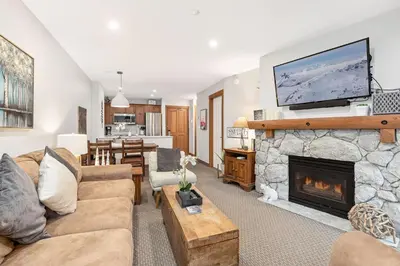 a living room with a fireplace with a tv above it at Lost Lake Lodge by Whistler Premier in Whistler