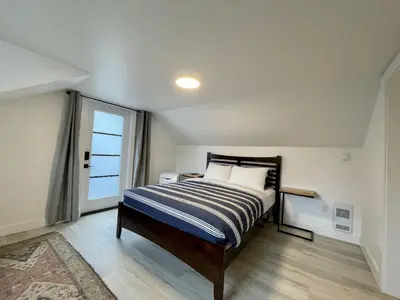 a small bedroom with a bed and a window at Salt Loft - Oceanfront, Hot Tub And Firepit! in Ucluelet
