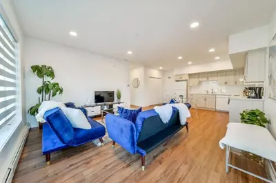 a living room with blue chairs and a kitchen at Royal Blue Wild Oasis Corner PNHSE KingBed U/G Wi-fi in Edmonton