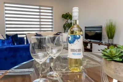 a bottle of wine sitting on a table with two wine glasses at Royal Blue Wild Oasis Corner PNHSE KingBed U/G Wi-fi in Edmonton