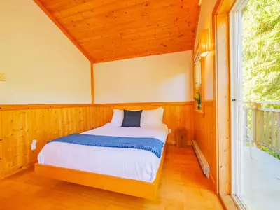 a bed in a small room with a window at The Perch Modern 2 Bed Cabin with Patio and Hot Tub in Ucluelet