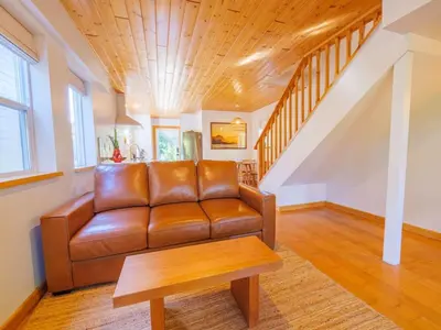 a living room with a brown leather couch and a table at The Perch Modern 2 Bed Cabin with Patio and Hot Tub in Ucluelet