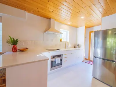 a kitchen with white counters and a wooden ceiling at The Perch Modern 2 Bed Cabin with Patio and Hot Tub in Ucluelet