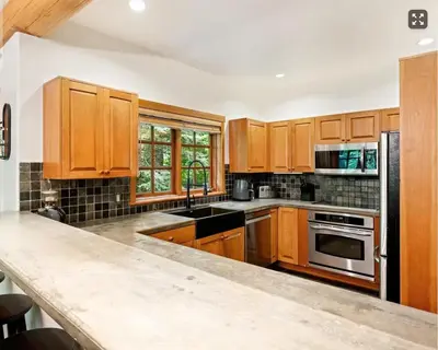 a kitchen with wooden cabinets and a black appliances at Ski In/Ski Out Luxury Home w/ jacuz/ fireplace in Whistler