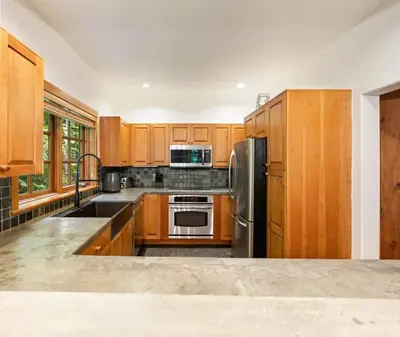 a kitchen with wooden cabinets and a stainless steel refrigerator at Ski In/Ski Out Luxury Home w/ jacuz/ fireplace in Whistler
