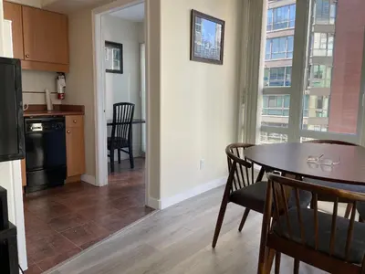 a kitchen and dining room with a table and chairs and a kitchen with a window at 1BD+Den condo, with free parking in Downtown! in Vancouver