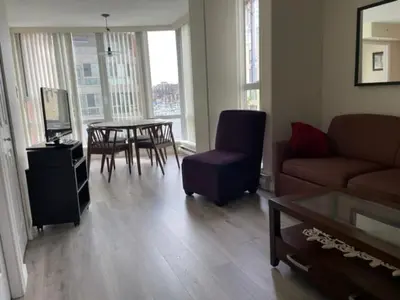 a living room with a couch and a table and chairs at 1BD+Den condo, with free parking in Downtown! in Vancouver