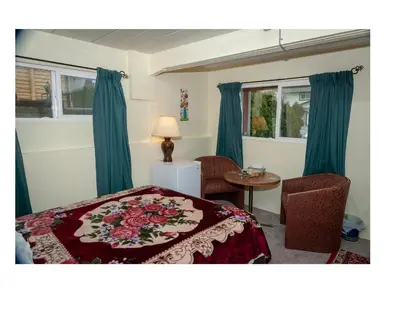 a bedroom with blue curtains and a bed and a table at Guest Suite - Private Retreat - J-1 in Abbotsford