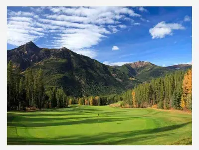 a green golf course with mountains in the background at Aurora Townhomes by StayIn in Panorama