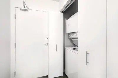 a kitchen with white cabinets and an open door at Stylish 1BR, Stampede & Free Parking by Doorbed in Calgary