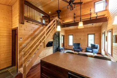 a log cabin with a staircase and a living room at The Qu INN - Cozy Cabin in Parson