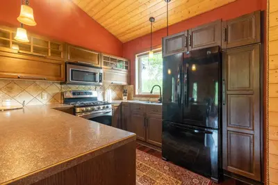 a kitchen with wooden cabinets and a black refrigerator at The Qu INN - Cozy Cabin in Parson