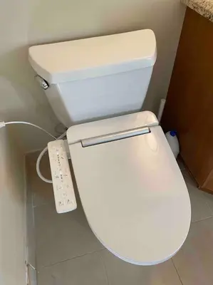 a white toilet in a bathroom with a remote control at Lucky suite, two-bedroom suite with independent entrance in Richmond close to YVR in Richmond