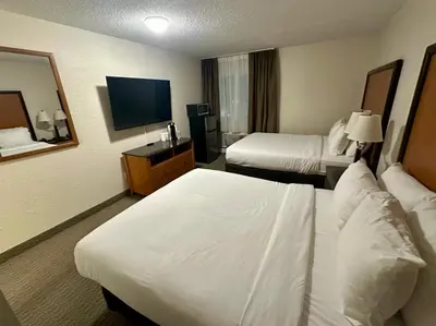 a hotel room with two beds and a flat screen tv at Anavada Inn & Suites - Grande Prairie in Grande Prairie