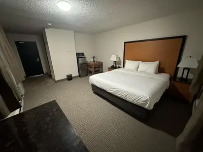 a hotel room with a large bed and a table at Anavada Inn & Suites - Grande Prairie in Grande Prairie