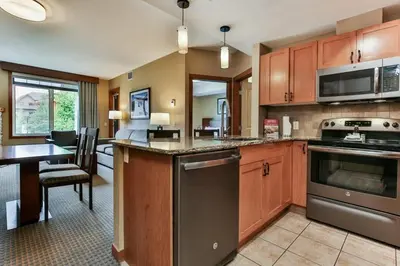 a kitchen with wooden cabinets and a table and a dining room at Luxury Falcon Crest Lodge 1 Bedroom 1 Pullout Kitchen Hot Tub in Canmore