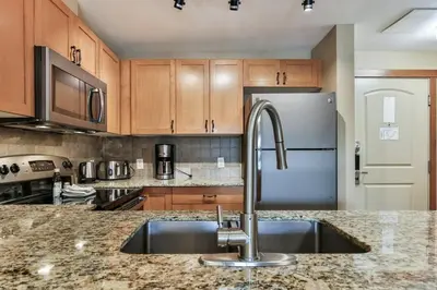 a kitchen with a sink and a refrigerator at Luxury Falcon Crest Lodge 1 Bedroom 1 Pullout Kitchen Hot Tub in Canmore