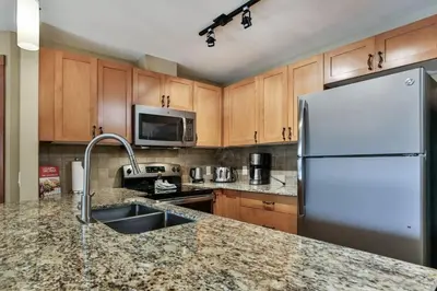 a kitchen with a sink and a refrigerator at Luxury Falcon Crest Lodge 1 Bedroom 1 Pullout Kitchen Hot Tub in Canmore