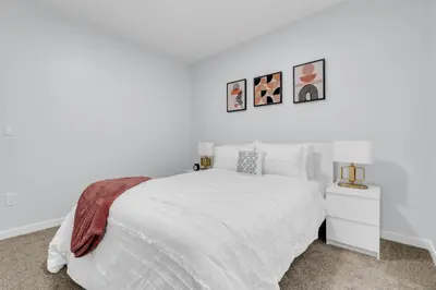 a white bedroom with a white bed and two pictures on the wall at You will love this 2BR Guest Suite in SE Calgary in Calgary