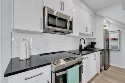 a kitchen with white cabinets and a microwave at You will love this 2BR Guest Suite in SE Calgary in Calgary
