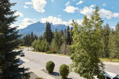 a street with trees and mountains in the background at Beautiful Renovated Wolf 2Bed 2Bath in Canmore