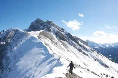 a man standing on top of a snow covered mountain at Beautiful Renovated Wolf 2Bed 2Bath in Canmore