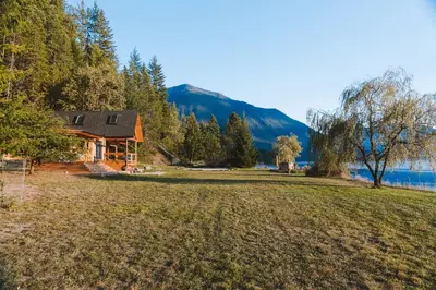 a cabin in the woods with a large grass field at The Kootenay Lake House - A Private Luxury Retreat in Nakusp