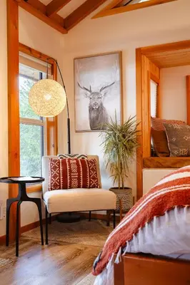 a bedroom with a bed and a chair and a table at The Kootenay Lake House - A Private Luxury Retreat in Nakusp