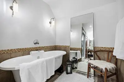 a white bathroom with a tub and a mirror at Luxury Penthouse At Solar A Resort And Spa in Canmore