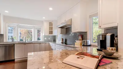 a kitchen with white cabinets and a book on a counter at \u6e29\u897f\u533a\u8c6a\u534e\u522b\u5885\u9644\u6709\u6309\u6469\u6d74\u7f38\u94a2\u7434\uff0c\u63a5\u8fd1\u673a\u573adowntown in Vancouver