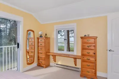 a bedroom with dressers and a window and a mirror at Kye Bay Winter Beach House by EMR Vacation Rentals in Comox